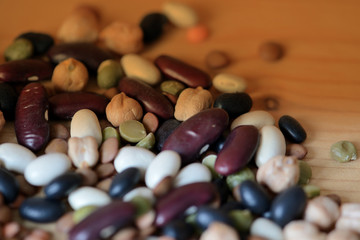 Different beans scattered on a wooden surface close-up. Naturel organic food background