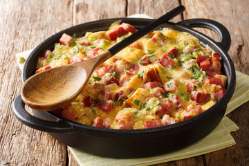 Tasty hot homemade strata with ham, onions, cheese and eggs close-up in a pan on the table....