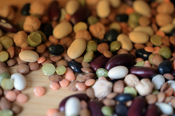 Different beans scattered on a wooden surface close-up. Naturel organic food background