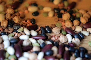Different beans scattered on a wooden surface close-up. Naturel organic food background