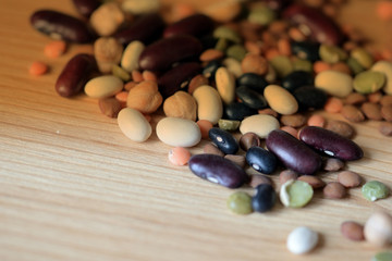 Different beans scattered on a wooden surface close-up. Naturel organic food background