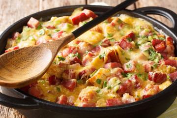 recipe for a simple strata with ham, bread, onions, cheese and eggs close-up in a pan. horizontal