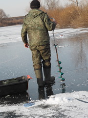 Naklejka premium winter fishing on ice on a river and lake by a fisherman