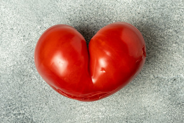 Ugly Organic Vegetable - Single red heart-shaped tomato on a gray background