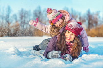 Little girl and her mother playing outdoors at sunny winter day. Active winter holydays concept. - 305622794