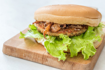 Homemade Salmon Burger with Tartar Sauce, Onion and Lettuce on Marble Board.
