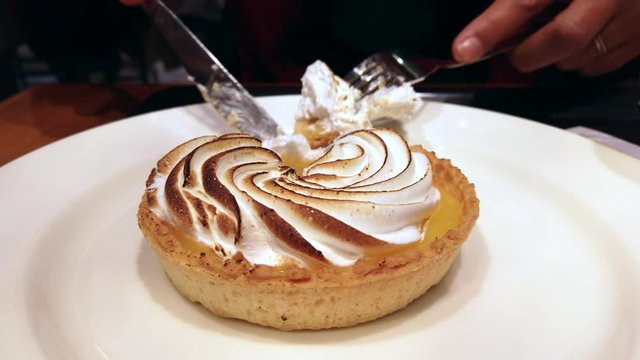 Someone eating a lemon meringue tart