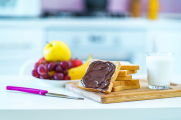 Toast bread with nut chocolate cream, fruits and a glass of fresh milk for a sweet healthy breakfast