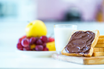 Bread with chocolate paste, fruits and a glass of fresh milk for a dessert