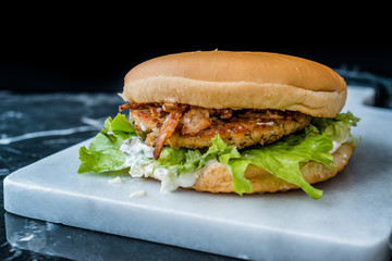 Homemade Salmon Burger with Tartar Sauce, Onion and Lettuce on Marble Board.