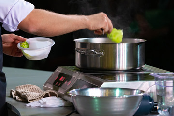 Cook is preparing dinner. Man is cooking soup. Cooking in the restaurant kitchen. Cook's career. Field Service. Man puts paste in a pan. Cooking vegetable soup. Chef shows masterclass.