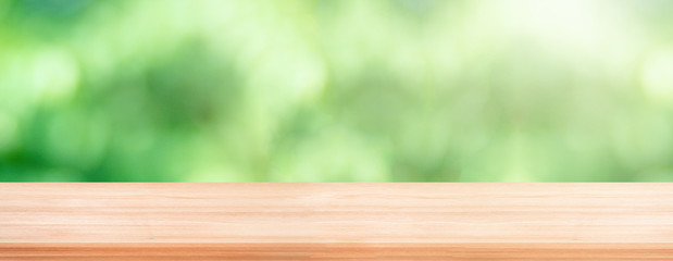 Wooden table with blurry green natural and bokeh light in background.