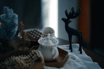 Christmas cat and holiday decorations. Christmas sill life card. Kitty and golden chain. Low key picture. Cozy house. candle and a cup of tea. cat is sitting on the table