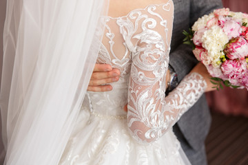 Wedding day. Groom embracing bride in white wedding dress with wedding bouquet