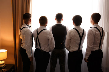Groom and groomsmen looking at window after wedding ceremony
