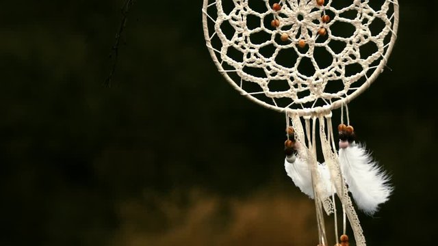 Dramatic reveal of dreamcatcher hanging in breeze, slow-mo, tilt