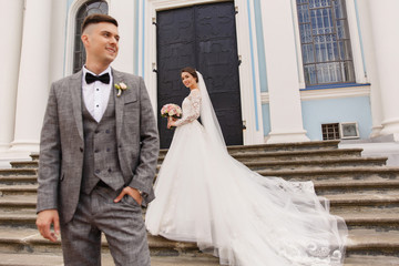 Wedding photography of stylish newlyweds. Beautiful wedding couple, elegant groom in grey suit and...