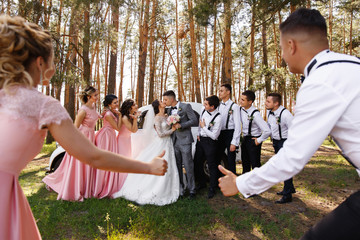 Naklejka na ściany i meble Happy wedding. Bridesmaids and groomsmen having fun when bride and groom kisses