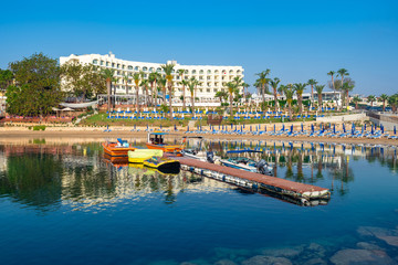 Fototapeta na wymiar Republic of Cyprus. Protaras. Resort hotel near the beach. Hotel off the coast of the Mediterranean Sea. Beach in the city of Protaras. Boats at the pier. A pier near the beach. Travel to Cyprus