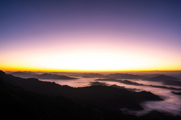 Beautiful scenic sunrise view above the mountains with cloud moving or mist.Colorful orange and violet sky with sunlight in high peak of heaven hill.Nature background concept