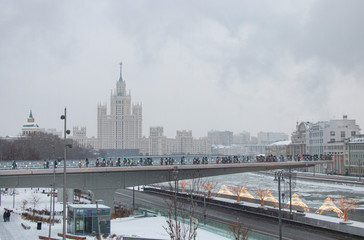 Tourists walk on a bridge over a river in Moscow. Zaryadye in a ziny foggy morning.