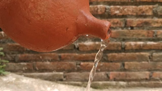 Pouring water from a clay jug 
