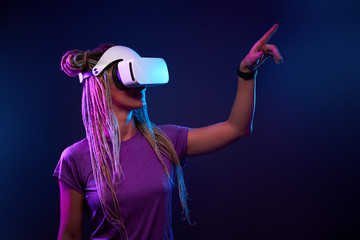 Woman is using virtual reality headset. Neon light studio portrait.