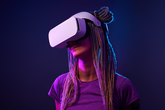 Fototapeta Woman is using virtual reality headset. Neon light studio portrait.