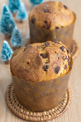 Close-up of two panettones, the first focused, with Christmas trees, on wooden table in vertical