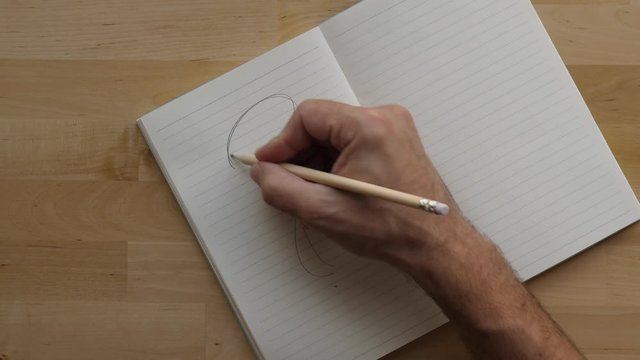 Man draw question mark on whole page over and over again, top down shot of typical notepad lying on wooden table of home office. Guy questioning himself, express feeling on paper