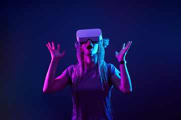 Woman is using virtual reality headset. Neon light studio portrait.