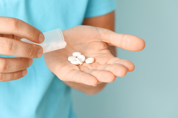 Man with pills on color background, closeup
