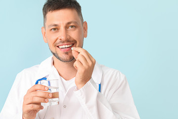 Doctor taking medicine on color background