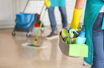 Female janitor with cleaning supplies in kitchen - obrazy, fototapety, plakaty