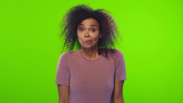 Indifferent puzzled African female shrugs shoulders, pursed lips, has clueless expression, can't make decision, chooses between two items, feels confused, dressed in casual clothes, on chroma key