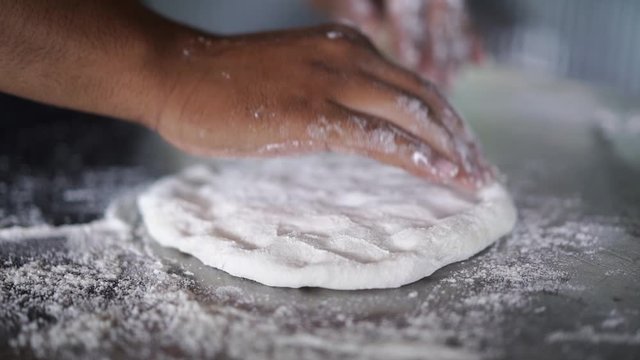 man thresh flour on stainless surface, prepare to make homemade style pizza