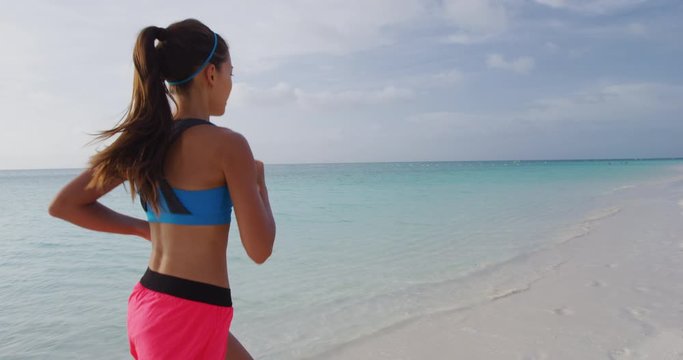 Runner woman running on beach at sunset enjoying fitness spors training workout run outside. STEADICAM SLOW MOTION, RED Cinema Camera.