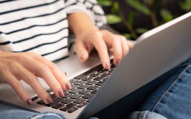 Closeup, Woman's hand type on computer laptop as she work from home due to Covid-19 pandemic, city...
