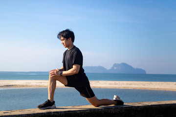 Asian male is stretching before doing work out ,jogging at seaside in the moring with beautiful sea...