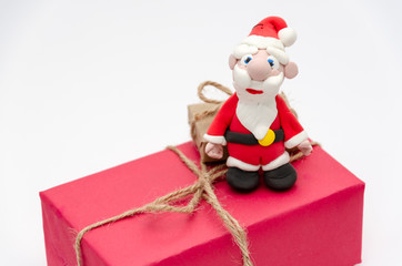 Santa Claus sitting on a big pink Christmas gift box on white background. Christmas and New Year holidays concept. Closeup. Copy space