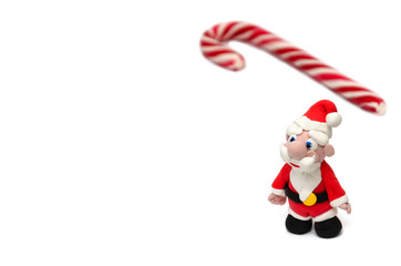 Santa Claus figurine and candy cane on white background. Christmas and New Year holidays concept. Festive background. Mockup. Copy space