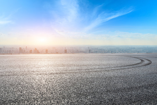 Asphalt race track ground and modern city skyline in Shanghai at sunset.