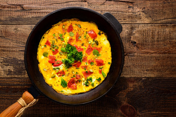 closeup omelet with old cast iron pan on wooden background with copy space