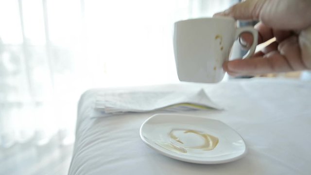 Busy day.Stack papers and coffee cups placed on the bed in the businessman's bedroom. The hand holding the document and bills quickly makes it known that it is a very busy day for this businessman.