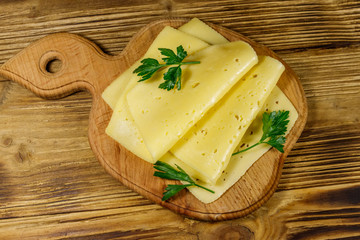Slices of cheese on cutting board on wooden table