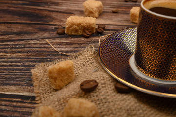 Coffee Cup, brown sugar and coffee beans on wooden background. Close up.