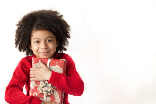  Festive christmas concept. Happy adorable african american child girl with christmas gift in hands isolated on white background