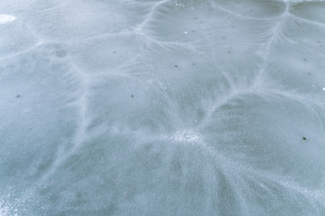 Frozen water on pond; bizarre forms of cracks on freezing lake; crystal clear ice with abstract pattern; blue, white, black colors; transparent cristals of water; form of new ice, lumps of frazil ice