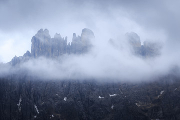 Mountain peak hiding behind the clouds and fog on the highland plateau in Dolomites, South Tyrol, Italy