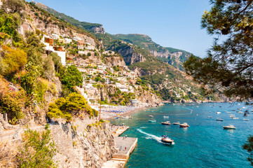 Amazing Italian Positano cityscape on rocky landscape, people on the beach, boats are coming and going to the sea tours, promenades full of apartments and businesses